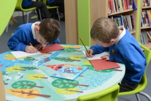 children writing at a table in primary school library