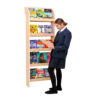 Secondary school student reading book in front of a library bookcase