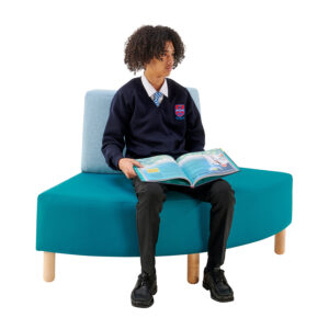 teenager reading and sitting on outer curved seat in school library