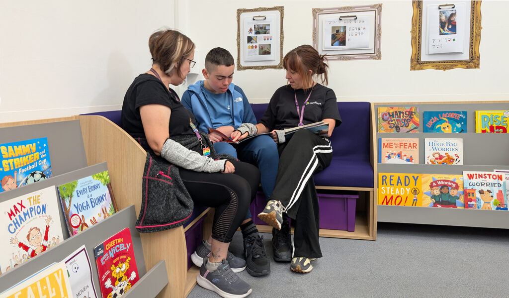 two teachers reading with boy in school library
