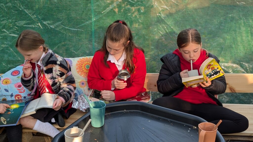 three girls reading books in outdoor school book club