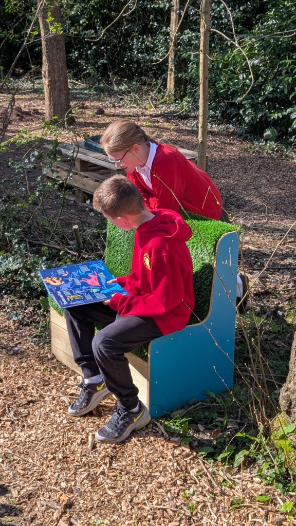 pupils reading outdoors on grass bench